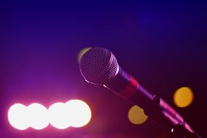 Close up photo of microphone with stage lights in the background